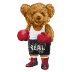 Urso de pelúcia boxeador, usando luvas vermelhas, camiseta branca e calças pretas com a palavra "REAL". Ideal para temas de esportes e diversão.