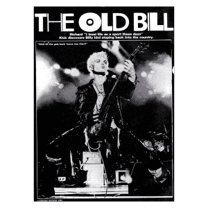 Imagem em preto e branco de um músico em performance enérgica, tocando guitarra em um palco iluminado. O músico, com cabelo platinado e estilização punk, exibe uma pose expressiva, enquanto a multidão ao fundo se aproxima. A imagem pertence à edição de agosto de 1984 da revista Zig Zag, destacando a volta de Billy Idol.